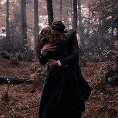 a man and woman hugging in the woods