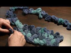 someone is crocheting something in the shape of a heart with blue and green yarn