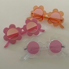 three pairs of pink and orange sunglasses with flower decorations on them, sitting next to each other