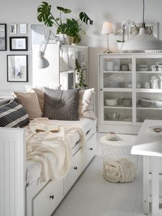 a bedroom with white furniture and lots of plants