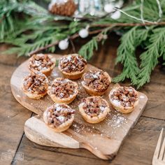 small pastries with powdered sugar on a cutting board next to pine branches and forks