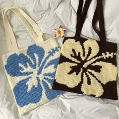 two crocheted purses sitting on top of a white bed next to each other