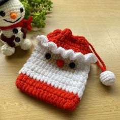 two small crocheted bags sitting on top of a wooden table next to a snowman