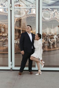 a man and woman standing in front of a carousel