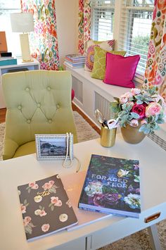 a living room filled with furniture and flowers on top of a white table next to a window