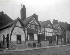 an old black and white photo of several buildings on the street in front of them