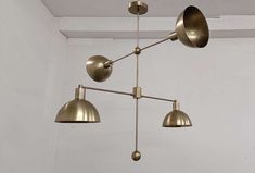 three brass colored lights hang from the ceiling in an empty room with white walls and flooring