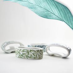 three bracelets with leaves on them sitting next to each other, one is green and the other is white