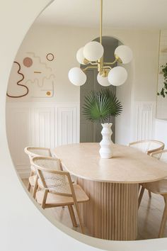 a dining room table with chairs and a potted plant in the center is seen through a circular window