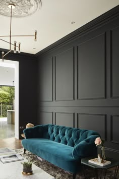 a living room with black walls and a blue couch in the middle, along with a marble coffee table