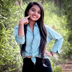 a young woman posing for a photo in front of some bamboo trees with her hand on her hip