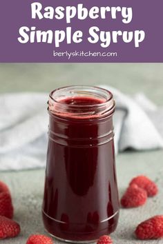 raspberry simple syrup in a glass jar with fresh raspberries around it