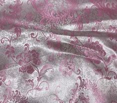 a pink and silver fabric with floral designs on the top, as well as an intricate design