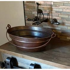 a large metal tub sitting on top of a wooden counter next to a faucet