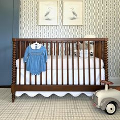 a baby's room with a crib, toy car and pictures on the wall