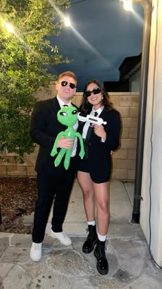 a man and woman dressed in costume posing for a photo with a stuffed animal frog