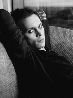 a black and white photo of a man laying on a couch with his arm up