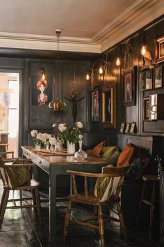 a dining room table with chairs and pictures on the wall above it, along with other furniture