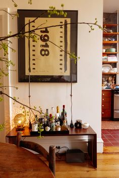 a wooden table topped with lots of bottles next to a painting on the wall above it