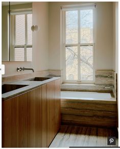 a bath tub sitting under a window next to a sink and counter top in a bathroom