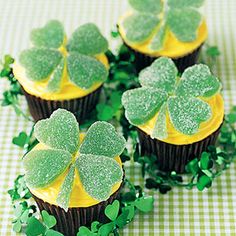 cupcakes decorated with green frosting and shamrock leaves on a checkered tablecloth