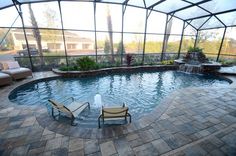 an indoor swimming pool with two lounge chairs next to it