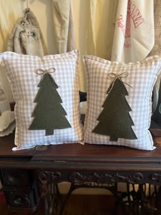 two pillows with christmas trees on them sitting on a table