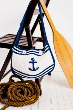 a crocheted bag sitting on top of a chair next to a wooden paddle