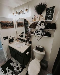 a white toilet sitting next to a sink in a bathroom under a mirror and lights