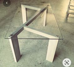 a glass table sitting on top of a cement floor next to a stepladder