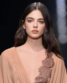 a woman with long hair and brown dress on the runway