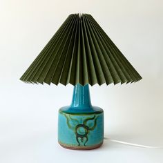 a blue table lamp with a green shade on it's base and a white background