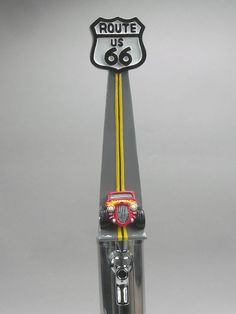 a route 66 sign on top of a glass vase with a yellow tube and car in it