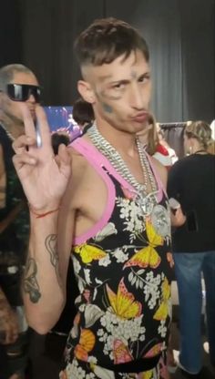 a man with tattoos on his face and arm standing in front of a group of people