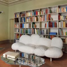 a white couch sitting in front of a book shelf filled with books