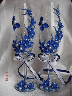 two wine glasses decorated with blue flowers and pearls