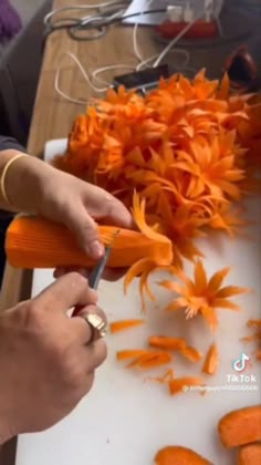 a person cutting carrots with a pair of scissors on a counter top next to orange flowers