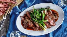 a white plate topped with meat and veggies on top of a blue table cloth