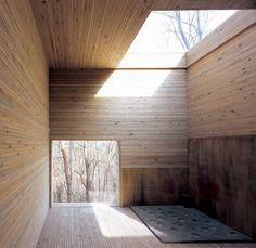 an empty room with wooden walls and flooring in the center is lit by sunlight