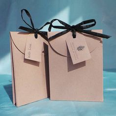 two brown paper bags with black ribbons tied around them on a blue background, one is open and the other has a tag attached to it