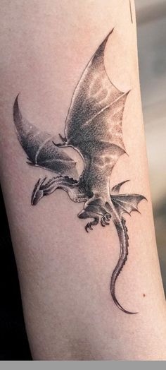 a black and white photo of a dragon tattoo on the arm