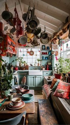 a kitchen filled with lots of pots and pans hanging from the ceiling next to a dining room table