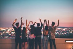 a group of people standing on top of a roof with their hands in the air