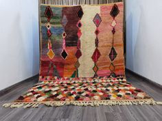 a multicolored area rug with fringes on the floor in front of a white wall