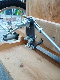 a bike wheel is attached to the side of a wooden bench with two wrenches on it