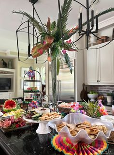 a table filled with plates and food on top of a black counter next to a chandelier