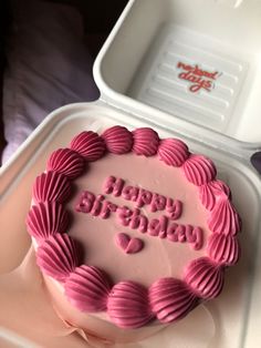 a birthday cake with pink icing in a plastic container