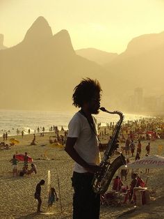 a man standing on top of a beach next to a saxophone