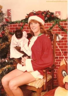 a woman sitting on a chair with a cat in her lap and christmas decorations around her