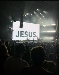 a large group of people sitting in front of a big screen with jesus on it